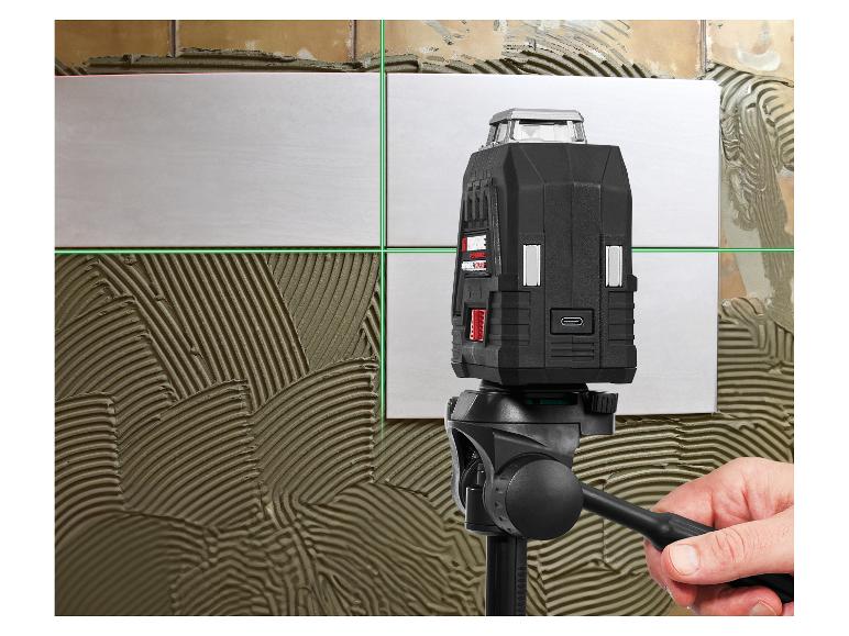 Laser croix sur trépied, projetant des lignes vertes sur des carreaux muraux avec adhésif.
