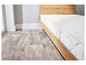 Un matelas blanc sur un sommier en bois dans une chambre avec un sol en bois.