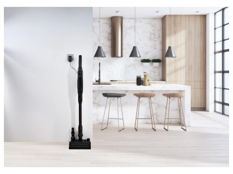 Aspirateur balai sans fil SilverCrest en charge dans une cuisine moderne.