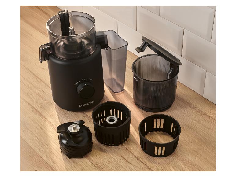 Robot culinaire noir avec accessoires démontés sur une table en bois.
