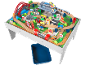Ensemble de train en bois sur table de jeu avec pont, gare, véhicules et figurines.