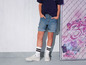 Une personne porte un short en jean et des baskets blanches.