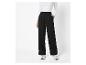 Pantalon noir à jambes larges et baskets blanches.