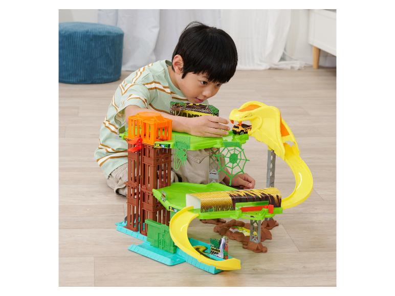 Un garçon joue avec un ensemble de jeu sur le thème de la jungle, avec une piste de voiture et un cobra.