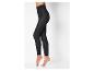 Une femme portant des leggings noirs moulants, debout sur un fond blanc.