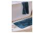 Serviette bleue drapée sur une baignoire avec un tapis de bain assorti sur le carrelage.