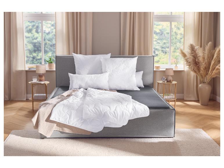 Lit continental gris avec literie blanche et jeté de lit dans une chambre avec fenêtre.