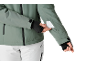 Personne en veste de ski verte et pantalon de ski blanc mettant une carte dans la poche de la manche.