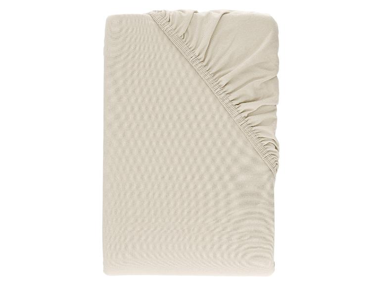 Drap-housse beige clair, plié avec le coin élastique visible.