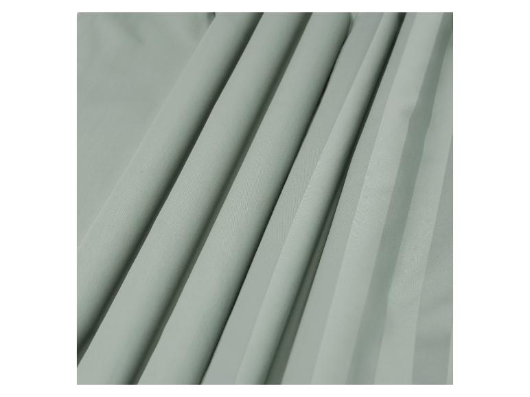 Gros plan d'un tissu plissé vert clair, montrant des plis doux et la texture.