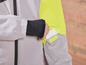 Une veste grise avec des détails jaunes et une carte blanche dans la poche.