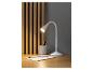 Une lampe de bureau blanche avec un bras flexible sur un bureau en bois.