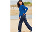 Une femme portant un pull bleu et un jean sur la plage.