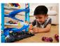 Garçon jouant avec une piste Hot Wheels à plusieurs niveaux et des voitures.