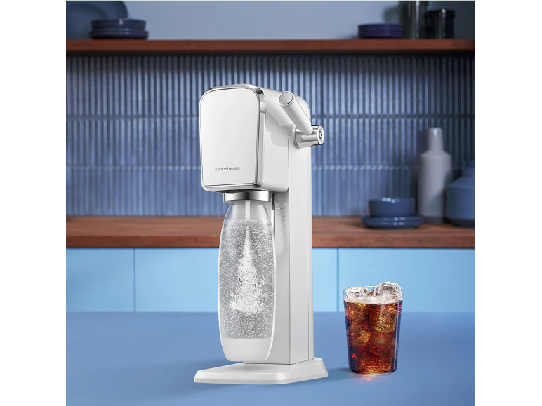 Machine à eau pétillante blanche avec une bouteille d'eau gazeuse et un verre de cola.