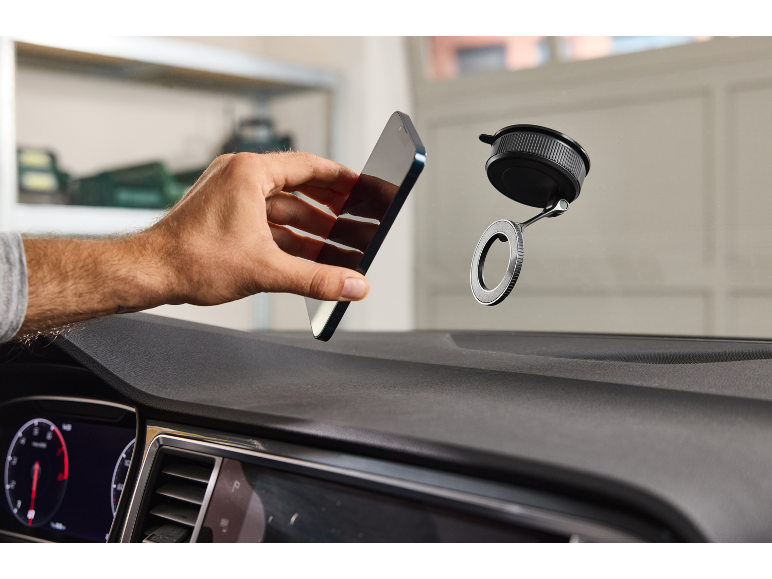 Main tenant un smartphone près d'un support de téléphone de voiture.
