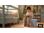 Enfant lit un livre assis sur un coffre à jouets dans une chambre d'enfant thème forêt.