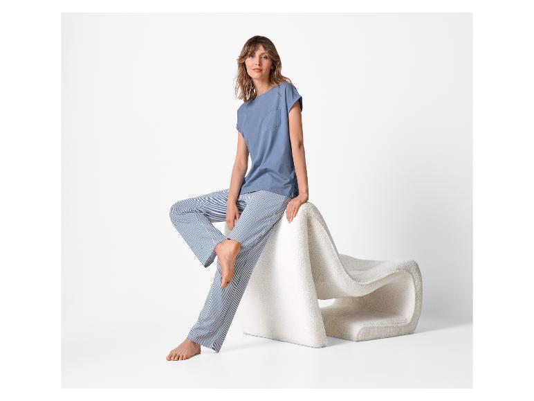 Femme en t-shirt bleu et pantalon rayé assise sur une chaise blanche.