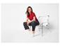 Femme en t-shirt rouge et jean foncé assise sur une chaise blanche.