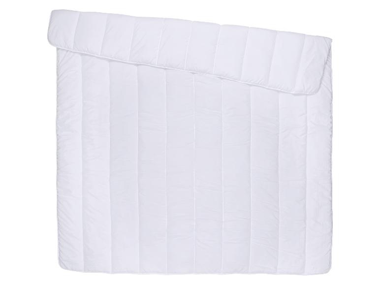Couette blanche matelassée, pliée en diagonale.