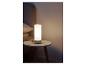 Lampe de chevet cylindrique blanche sur une table d'appoint ronde en bois.