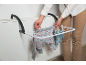 Femme étendant des vêtements de bébé sur un séchoir fixé à un radiateur.