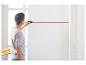 Homme utilisant un niveau laser pour projeter une ligne horizontale rouge sur un mur blanc.