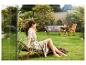 Femme se relaxant sur une chaise longue en bois dans un jardin verdoyant.