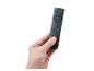 Main tenant une télécommande noire avec des boutons