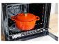 Une cocotte en fonte orange Silvercrest dans un four.