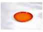 Une assiette en céramique orange sur une surface en marbre blanc avec des ombres subtiles.