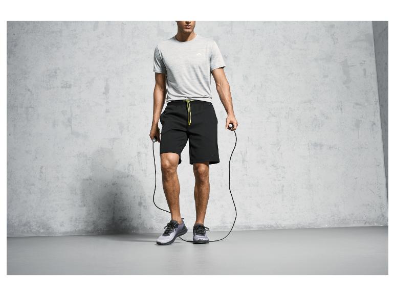 Un homme avec un short noir, un t-shirt gris et une corde à sauter.