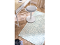 Tapis bleu clair à motifs sur parquet avec un bureau et un tabouret blancs.
