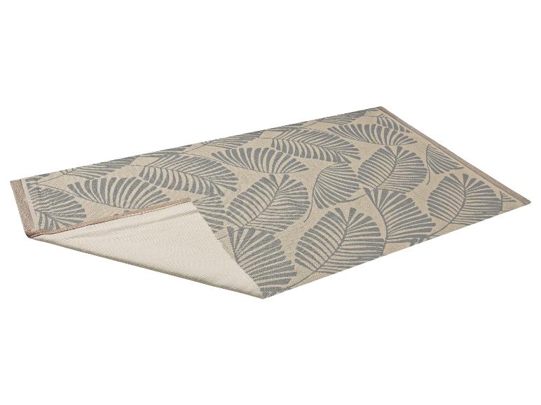 Tapis beige et gris à motif de feuilles, partiellement plié