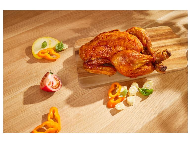 Poulet rôti, légumes (poivrons, maïs, tomates) sur planche en bois.