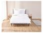 Draps blancs à volants sur un lit dans une chambre à coucher.