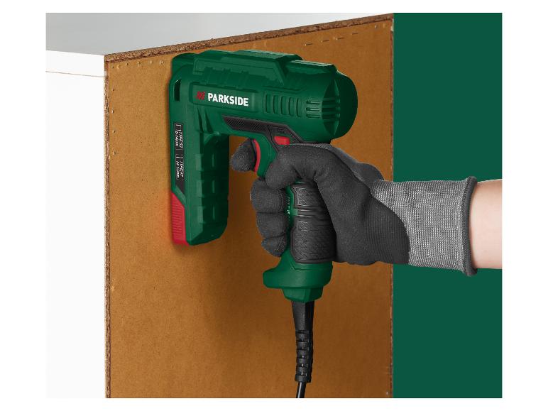 Une main tient une agrafeuse électrique contre une planche de bois.