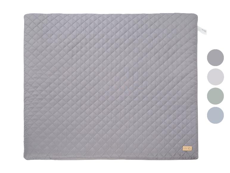 Couverture matelassée grise avec une petite étiquette et des échantillons de couleurs.