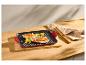 Poêle grill rouge avec poulet grillé et légumes sur une planche en bois.