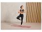 Femme faisant du yoga en leggings noirs et soutien-gorge de sport sur un tapis rose.