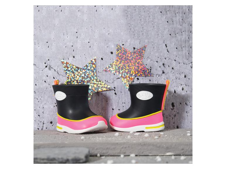 Bottes de pluie enfant noires et roses avec détails jaunes, avec des étoiles scintillantes en arrière-plan.