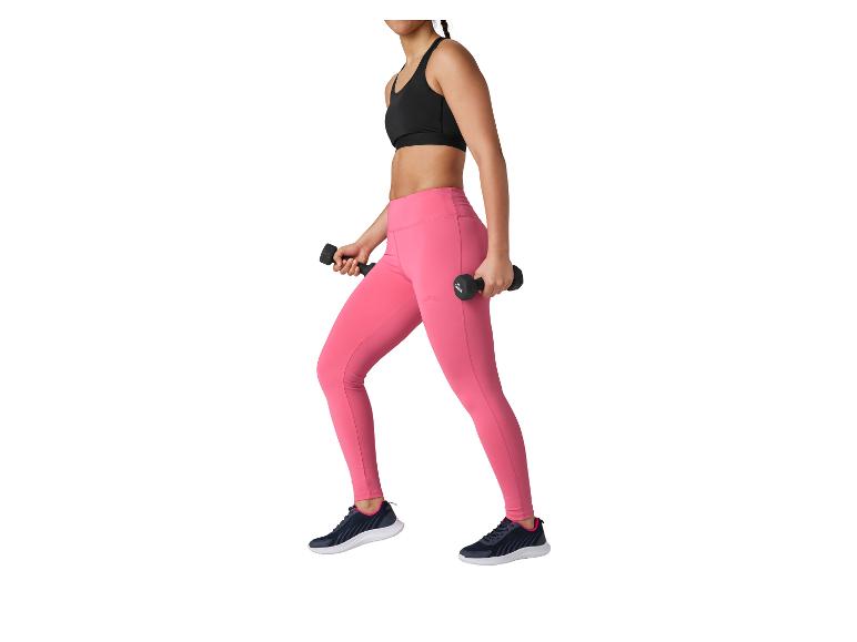 Femme en brassière noire et legging rose tenant des haltères.