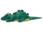 Une peluche verte en forme de dinosaure ou de dragon avec un ventre jaune, allongée sur le côté.