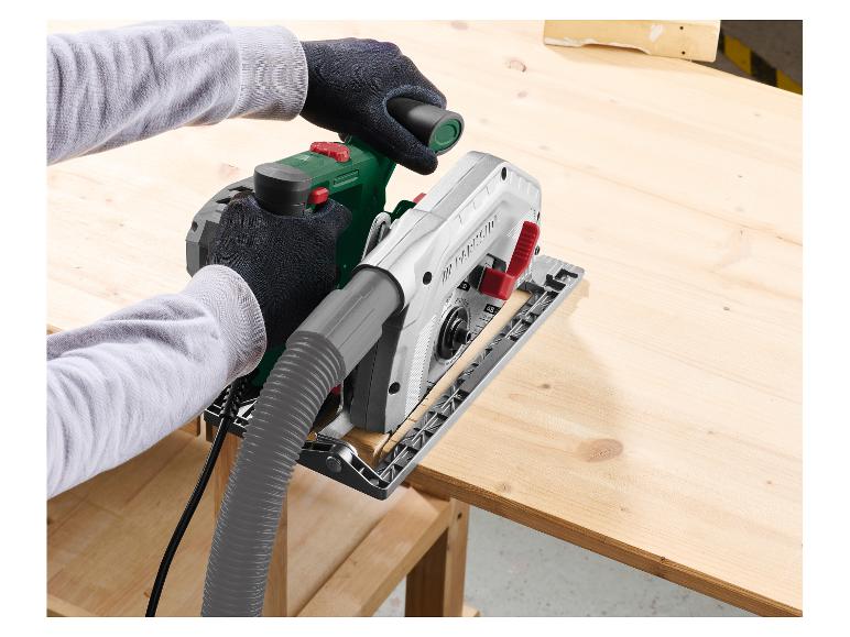 Mains coupant une planche de bois avec une scie circulaire et un tuyau d'extraction de poussière.