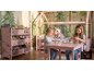 Deux filles jouent dans une chambre d'enfant rose avec un lit cabane et une étagère à jouets.