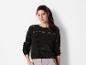 Une femme porte un pull noir ajouré.