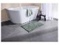 Tapis de bain vert clair sur un carrelage gris, près d'une baignoire.