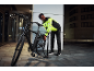 Homme en veste réfléchissante gonflant un pneu de vélo la nuit.