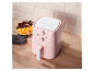 Une friteuse Silvercrest rose sur une table en bois à côté de frites et d'ailes de poulet.