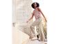 Femme portant un haut rose, un pantalon beige et des baskets blanches.